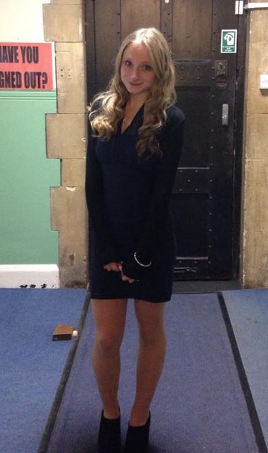 Charlotte, a white girl with long blonde hair, wearing a short navy dress and smiling at the camera.