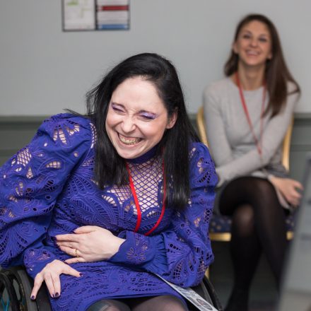 A white person in a wheelchair is grinning in a training session.