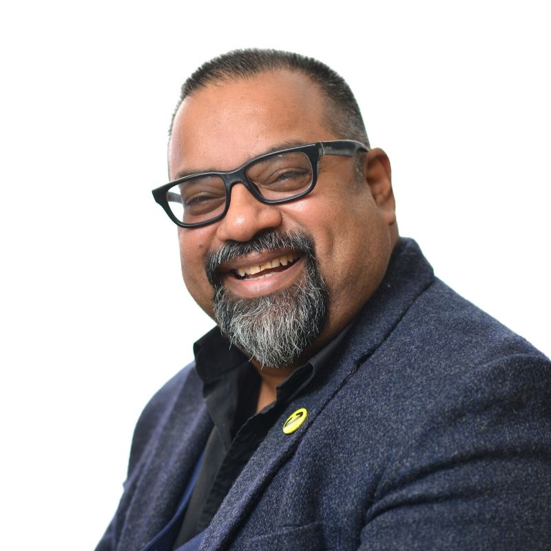 Profile photo of Atif, a brown man with dark hair and a beard, wearing glasses and a navy blue suit, smiling at the camera.