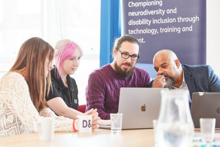 People in a meeting gather around a laptop.