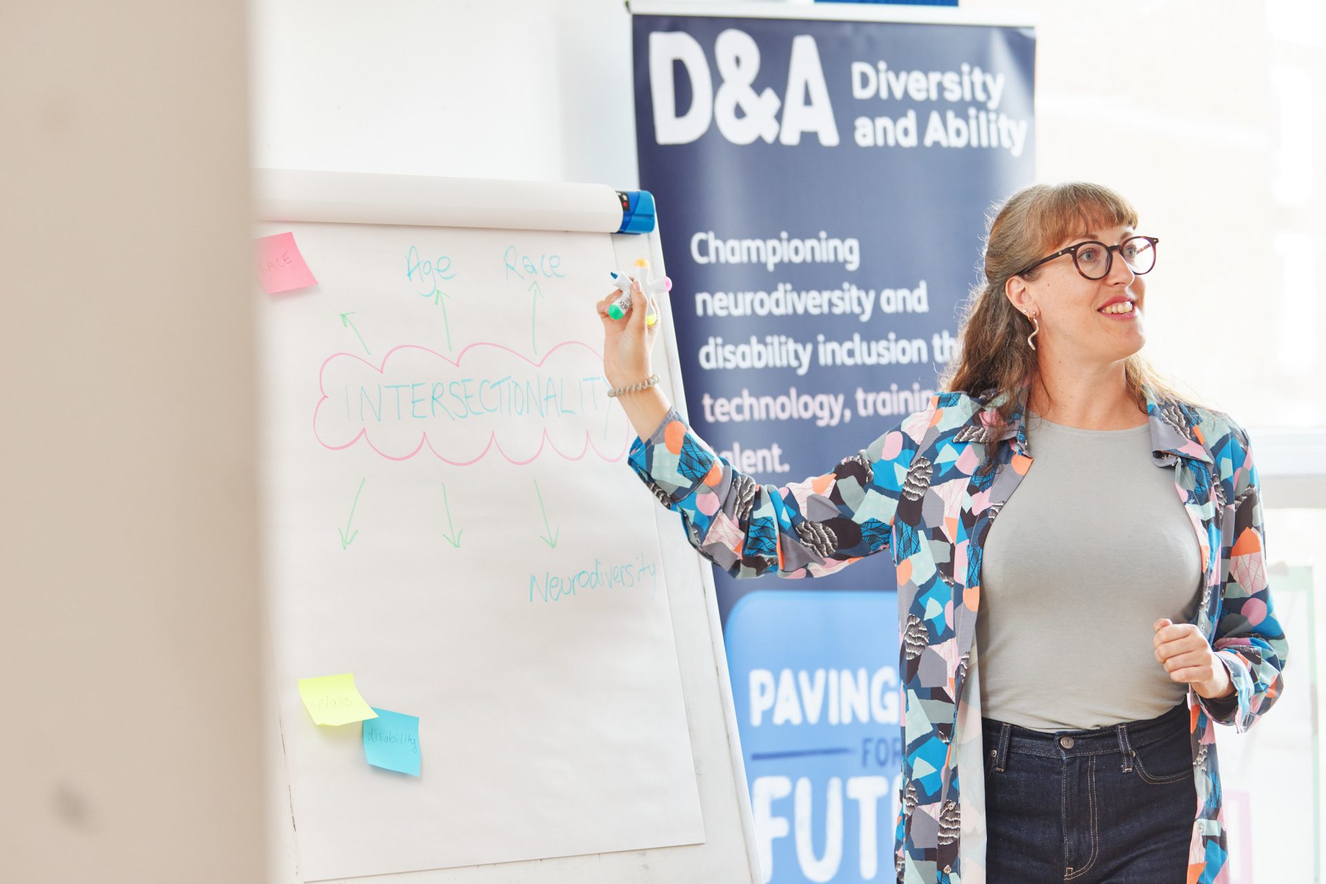 A woman presents from a whiteboard at a D&A training session. 