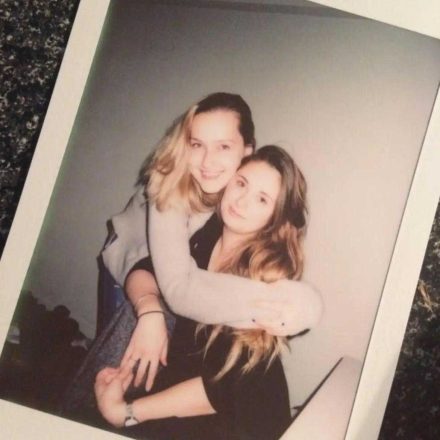 Brigit and another woman hug in a polaroid picture.