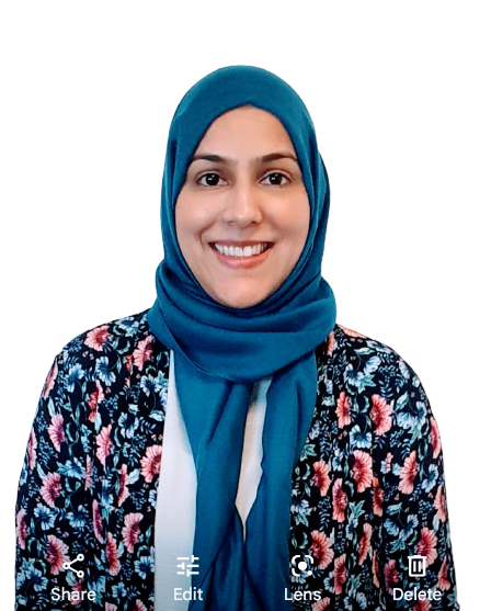 Profile photo of Iram, a British Pakistani woman with a blue headscarf, pink and blue flowery blouse, who is smiling at the camera.