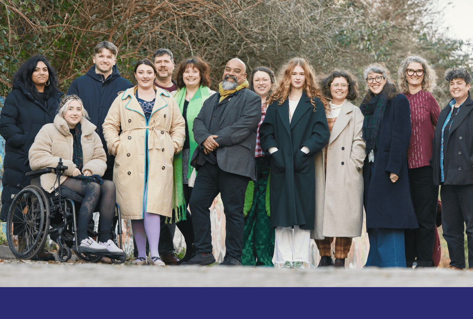 The D&A team outside their office in Brighton. They are moving towards the camera, but are looking at each other, chatting and smiling as they go. They are a diverse mix of ages, races, disabilities and genders.