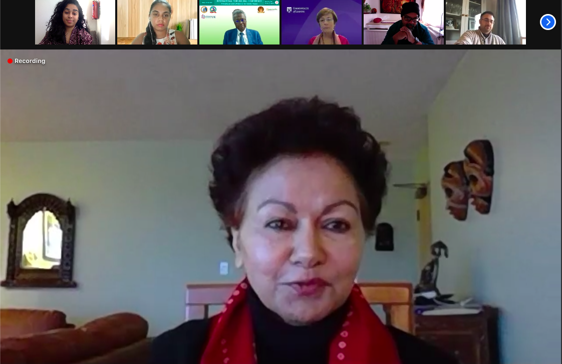 Screenshot of a Zoom call in speaker view. The speaker is Professor Asha Kanwar, a woman with short dark hair, wearing a bright red scarf. Her facial expression is positive and suggests she is mid-speech.
