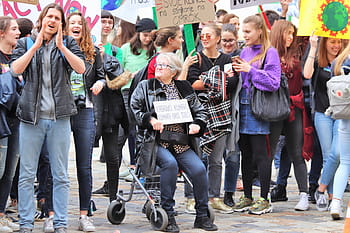 A lady sitting on her walker holding up a sign during a climate change protest