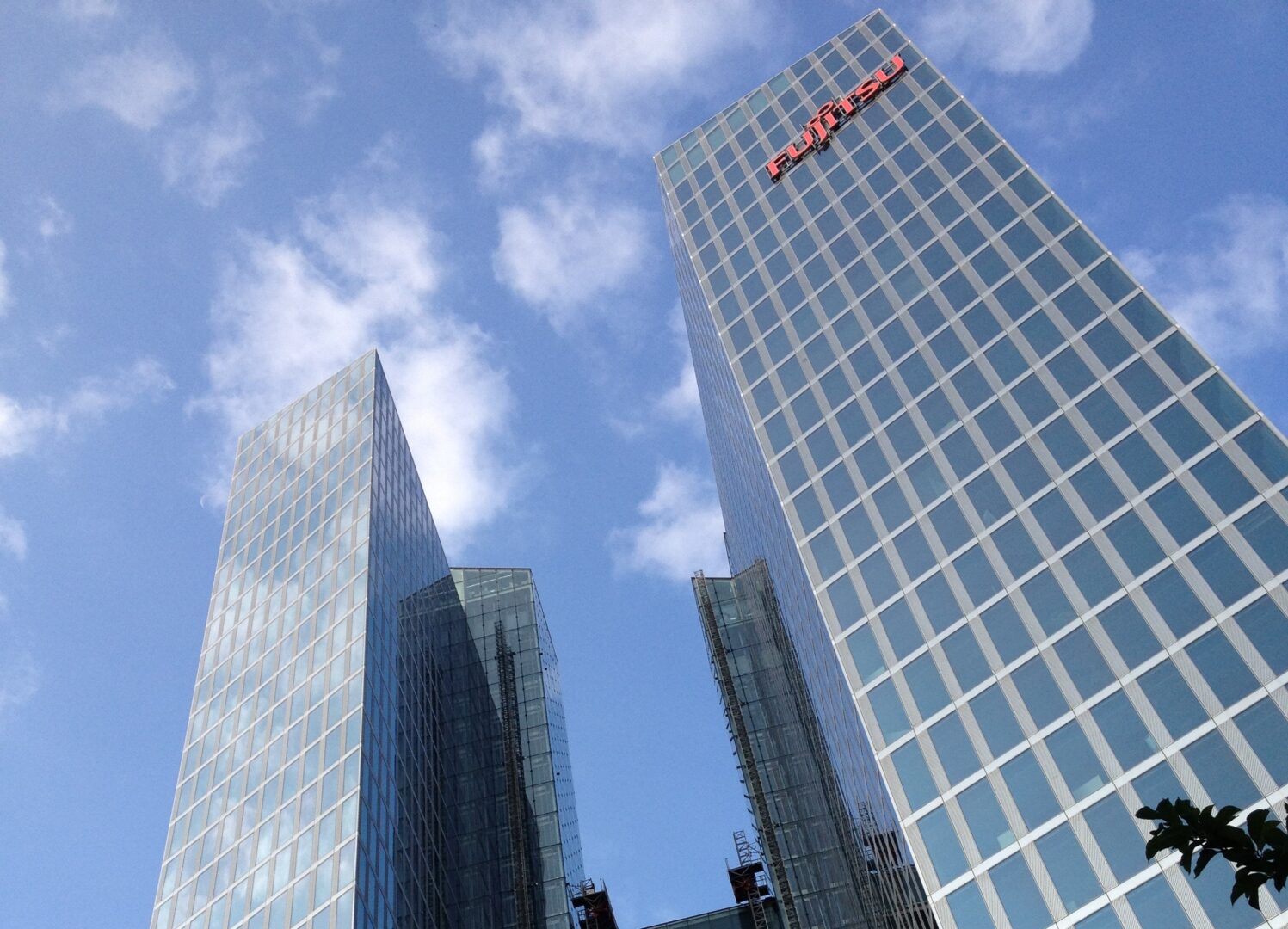 A photo taken from below, Fujitsu's skyscrapers. Behind them is a bright blue sky.